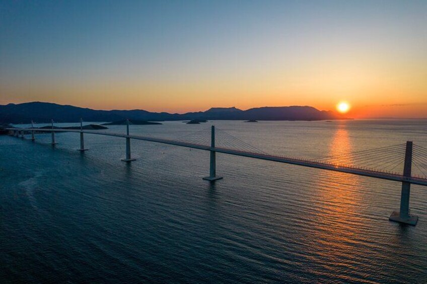 A suspension bridge over calm water at sunset. 2
