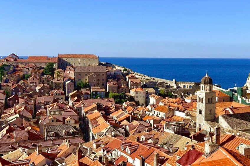 A coastal cityscape with historic buildings, a prominent church tower, and the sea in the background. 3