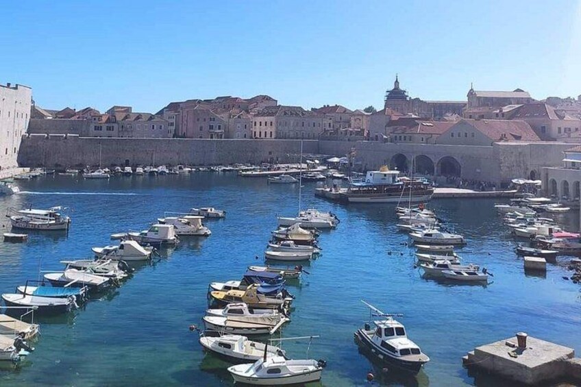 Un port où de nombreux bateaux sont amarrés, un ciel bleu et dégagé, et des bâtiments historiques en arrière-plan. 5