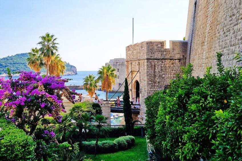 A historic stone building, lush greenery, and a coastal view. 4