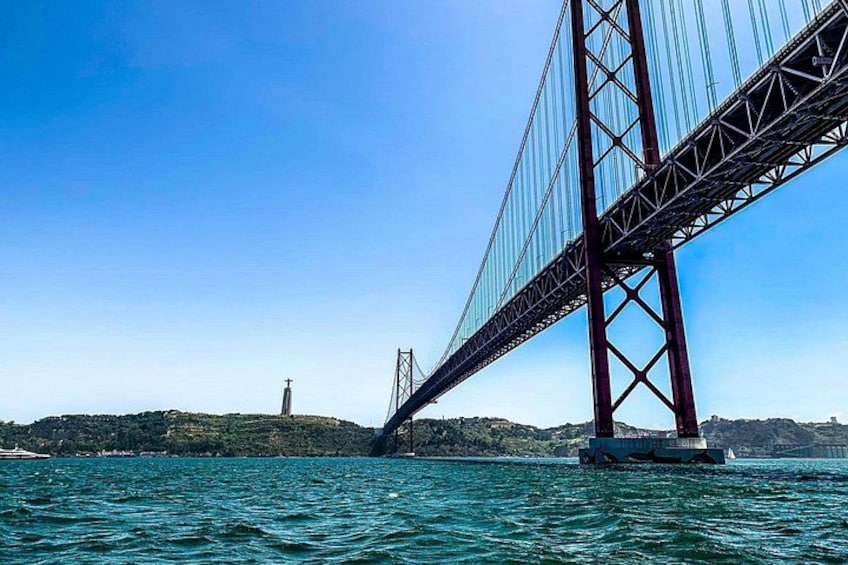 A large suspension bridge over a body of water with a lighthouse in the distance. 1