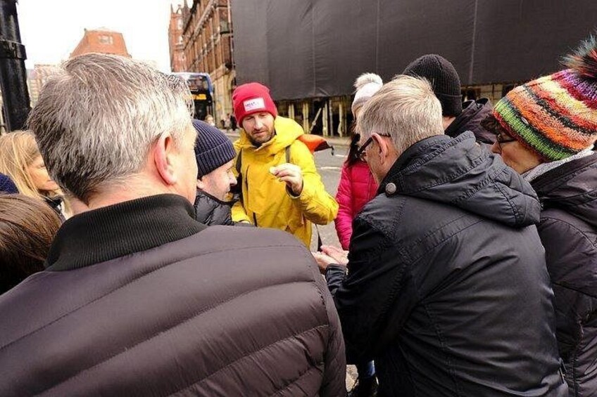 A group of people standing outdoors, some wearing winter jackets and hats. 4