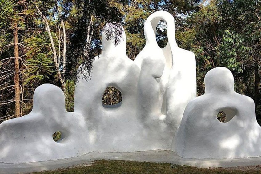 Una scultura astratta bianca con fori, sullo sfondo di alberi e vegetazione. 2