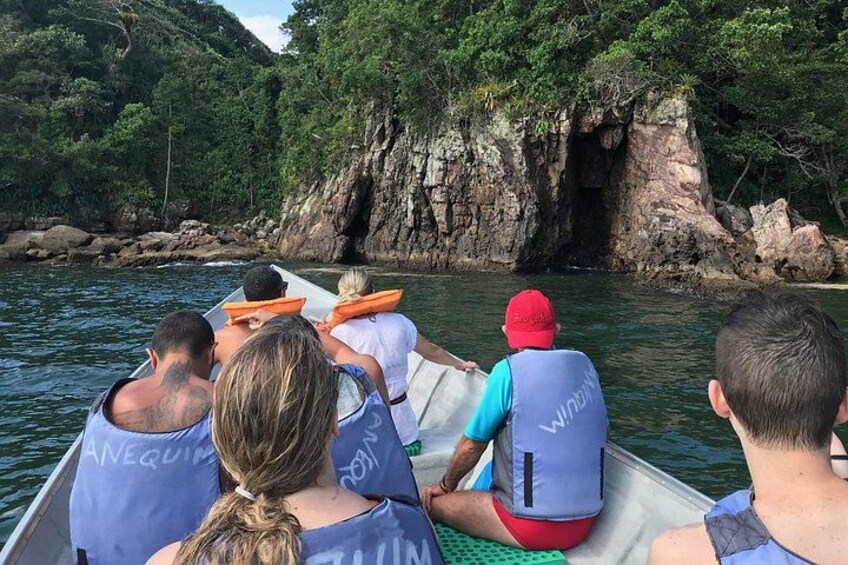 A group of people in a boat on a river, surrounded by rocky cliffs and dense greenery. 1