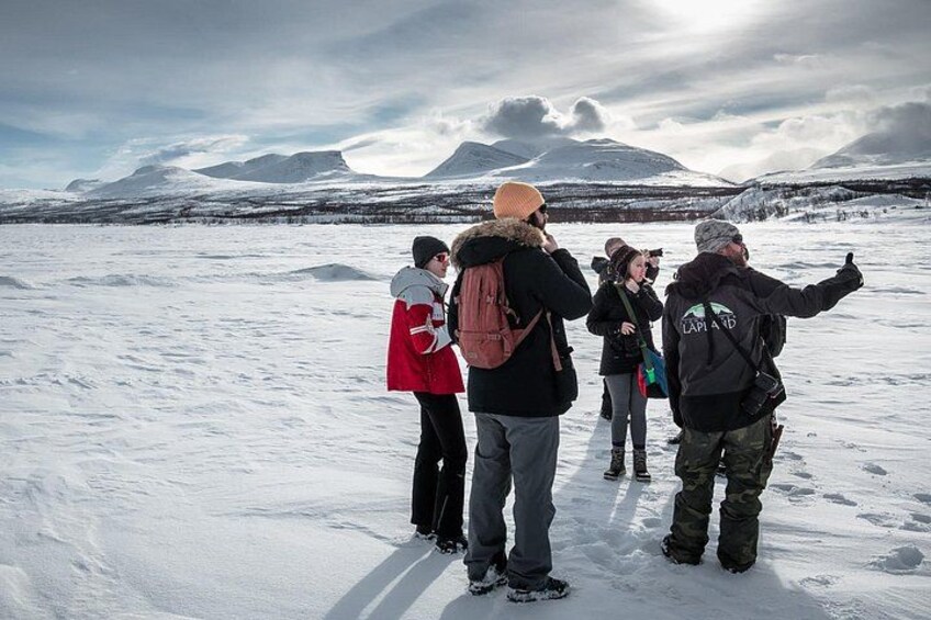 Eine Gruppe von Personen steht in einer verschneiten Landschaft, im Hintergrund sind Berge zu sehen. 1