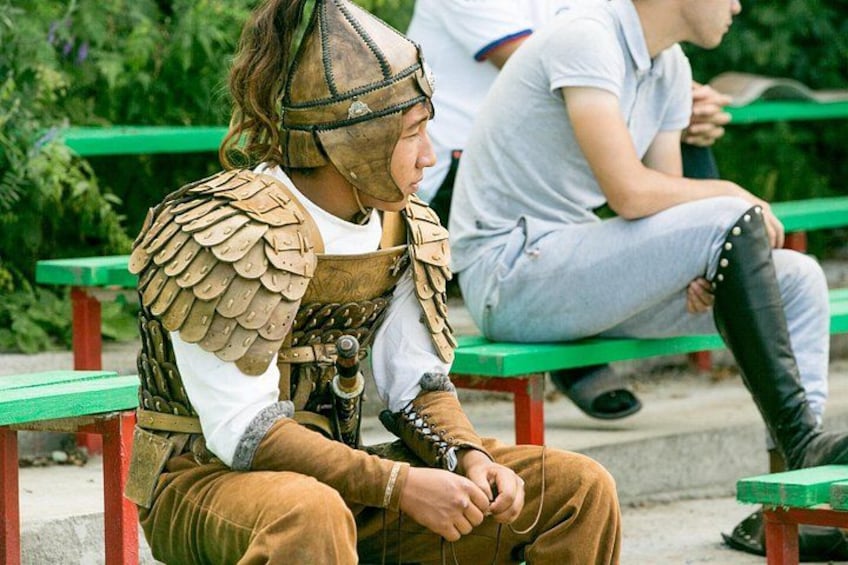 A person in a historical costume sitting on a bench. 2