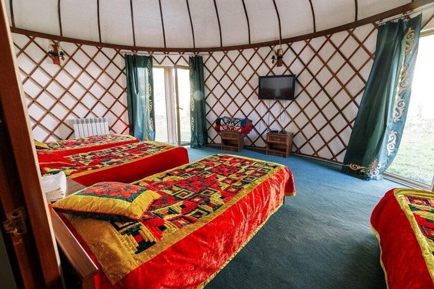 A yurt with two beds, a television, and a window. 3