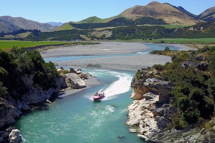 A river with a boat, surrounded by rocky cliffs and green hills. 3