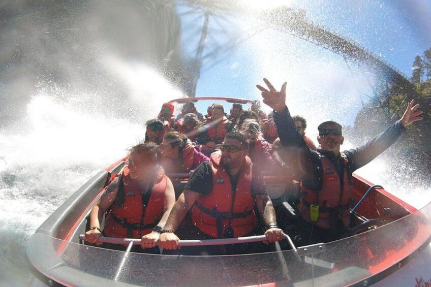 A group of people in a boat with water splashing around them. 2