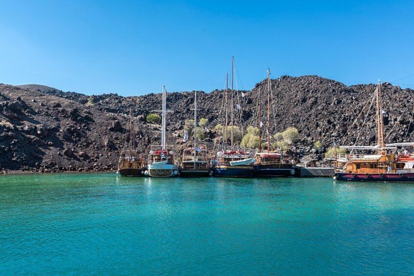 A harbor with several boats docked, rocky hills in the background, and clear blue water. 2