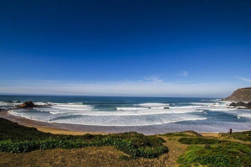 Un paysage côtier avec une plage, des vagues et une végétation verdoyante. 2