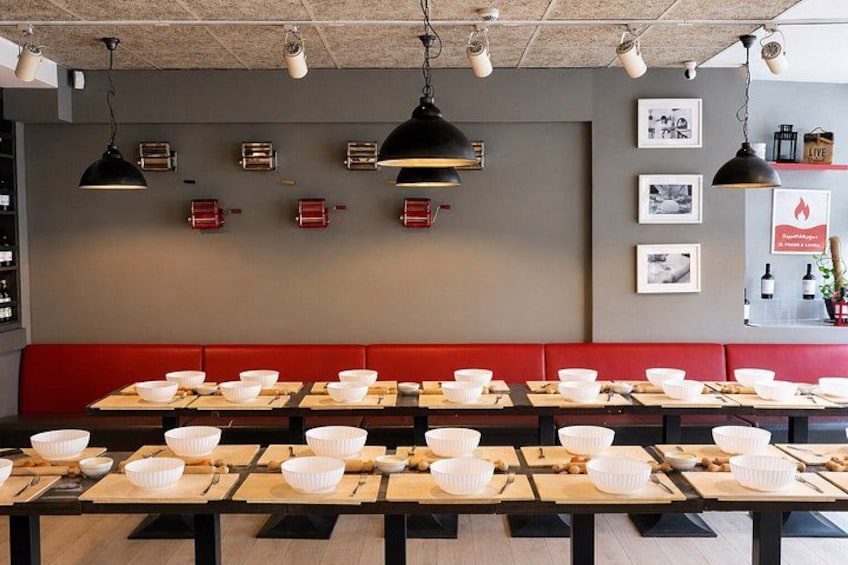 A restaurant interior with multiple tables, red booths, and hanging pendant lights. 2