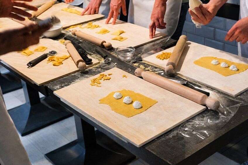 Un groupe de personnes prépare des aliments sur des planches en bois, à l’aide de rouleaux à pâtisserie et de pâte. 2