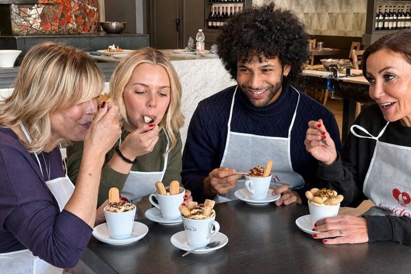 Cuatro personas sentadas en una mesa con platos de comida, usando delantales. 2