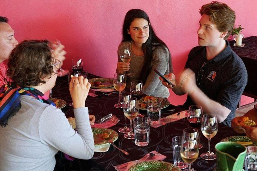 Un grupo de personas cenando en una mesa con copas de vino y platos de comida. 1