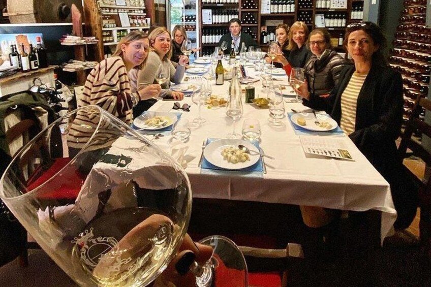 A group of people dining at a restaurant with wine glasses and bottles on the table. 1