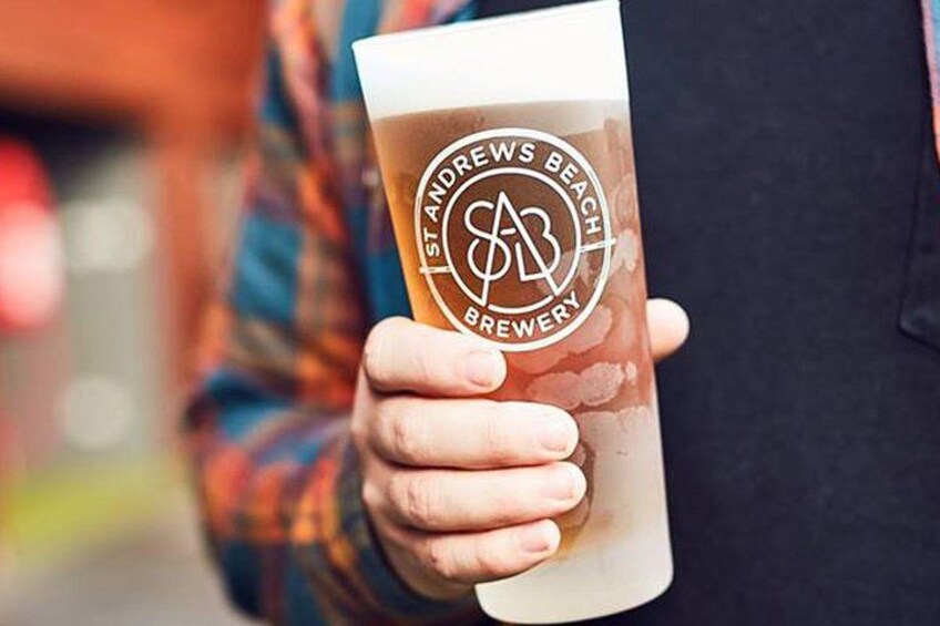Una persona sosteniendo un vaso con el logotipo que dice "Island Beaches Brewery". 3