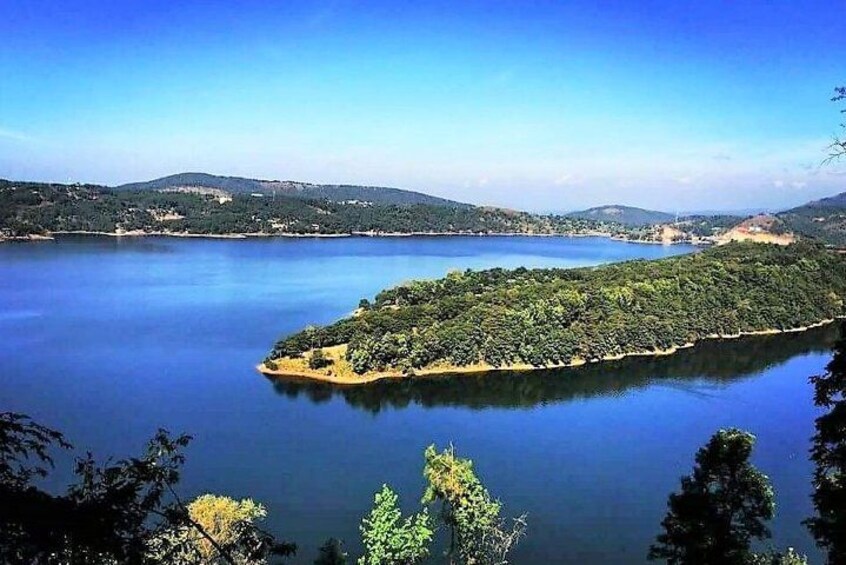 A calm lake surrounded by hills and dense greenery. 5
