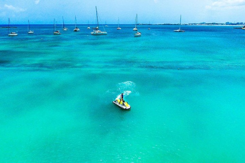 Un petit bateau sur des eaux turquoise, avec plusieurs voiliers en arrière-plan. 1