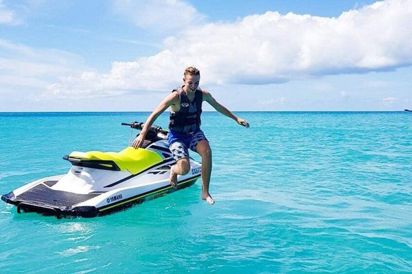 En person kører på en jetski i turkisblåt vand. 1