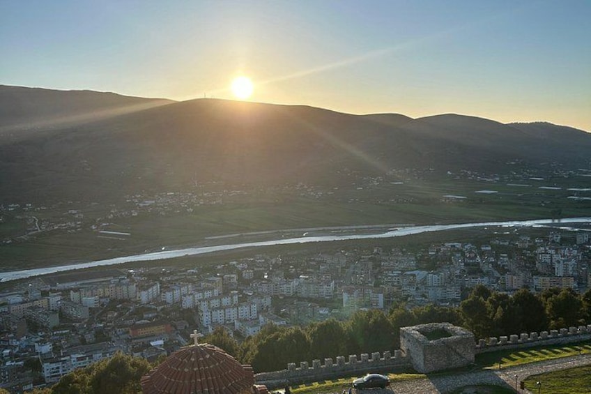 A cityscape with a river, mountains, and a sun setting in the background. 2