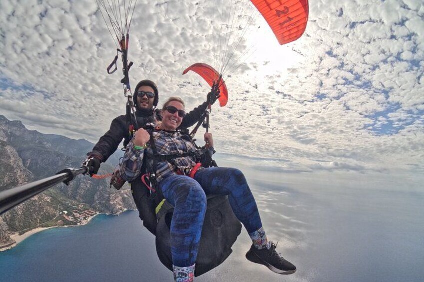 Twee mensen paragliden boven een bergachtig landschap, met water eronder. 2