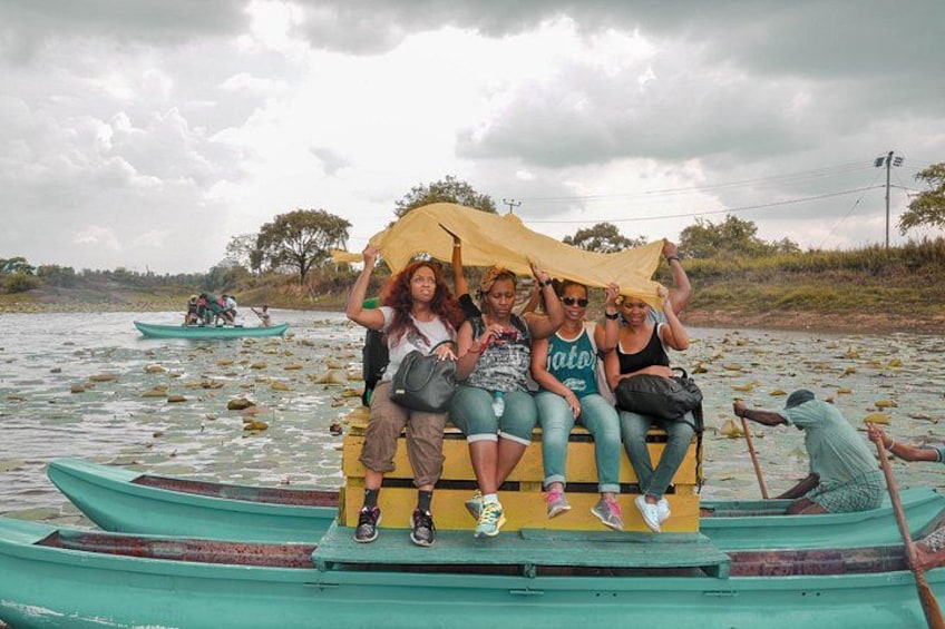Un grupo de personas en un bote con toldo, rodeado de agua tranquila y follaje. 2