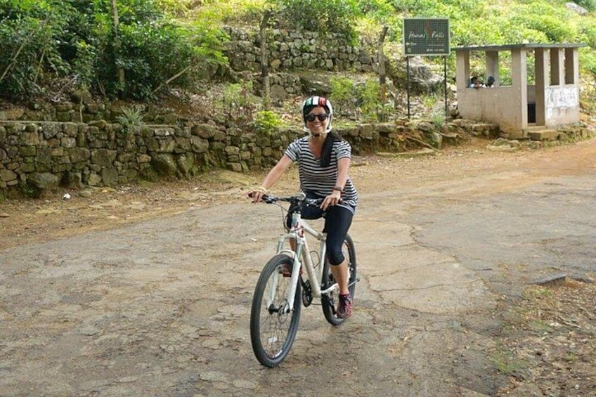 Eine Person fährt Fahrrad auf einem Feldweg, im Hintergrund eine Steinmauer und Grünpflanzen. 5