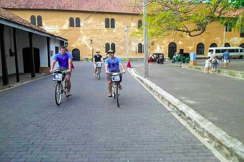 Dos ciclistas en una calle pavimentada con un edificio al fondo. 2