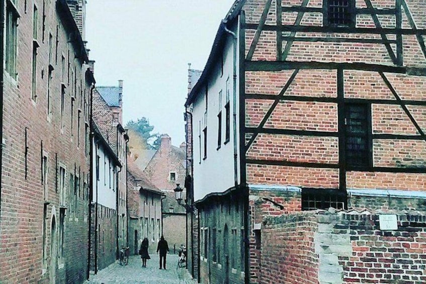 Una calle estrecha con edificios históricos, una persona caminando y un niño. 5