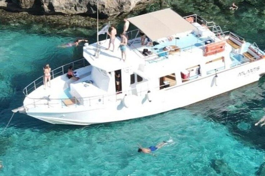 Een witte boot met mensen op het dek en in het water, omringd door helder turquoise water. 3