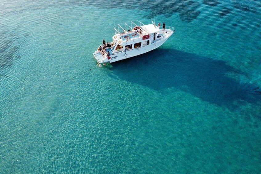 Een witte boot met passagiers, drijvend in helder turquoise water. 5