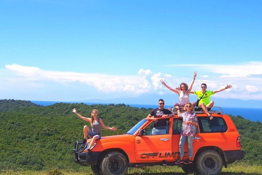 A group of people on an orange off-road vehicle with a forested landscape in the background. 4