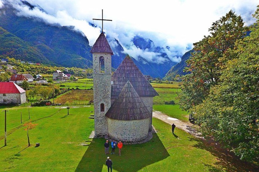 A church with a cross on top, surrounded by green fields and mountains in the background. 5