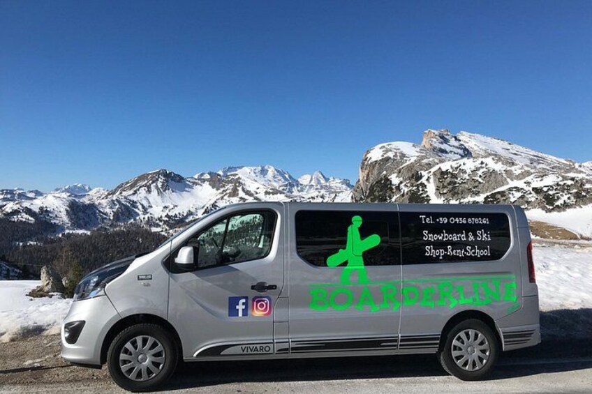 A silver van parked on a snowy road with a mountainous backdrop. 2
