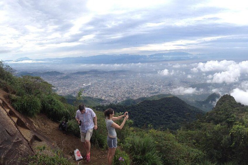 Zwei Personen machen ein Foto mit Blick auf eine Stadt und Berge, während Wolken ziehen. 4