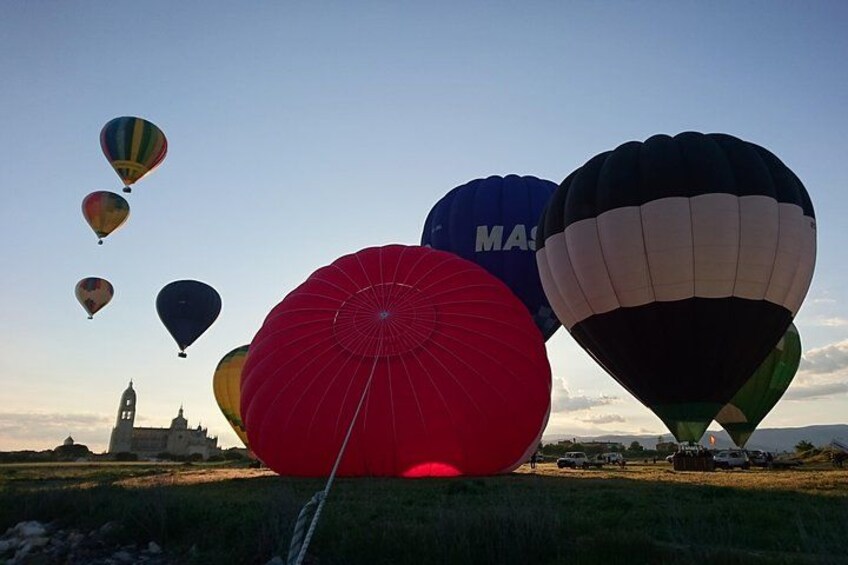 A field of hot air balloons with a large red one in the foreground and a clock tower in the background. 3
