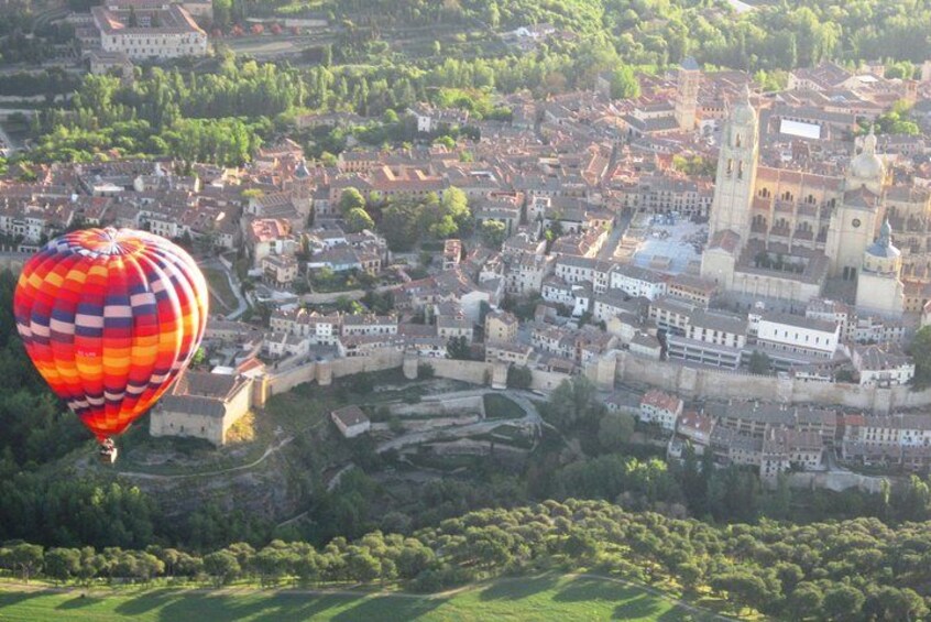 A hot air balloon over a historic town with a prominent church and castle. 2