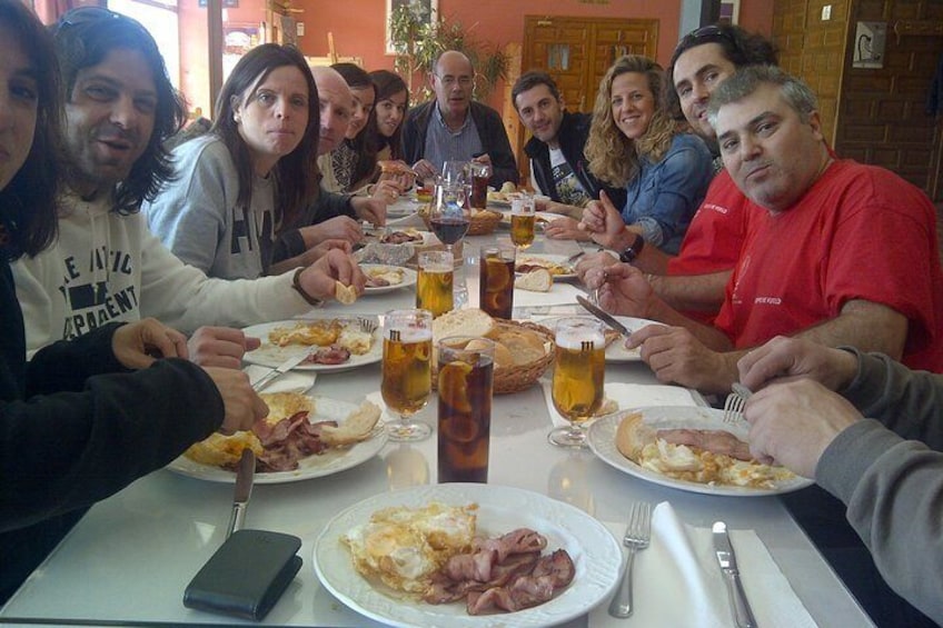 Un groupe de personnes est assis autour d’une table, devant de la nourriture et des boissons. 2