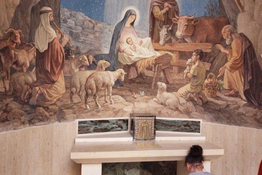 A mural with a nativity scene, a wooden cross, and a manger. 1