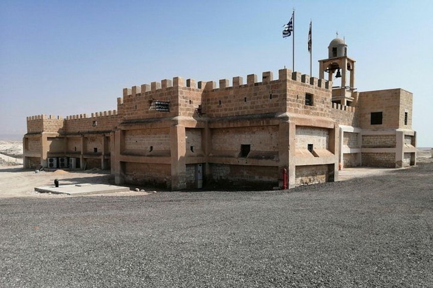 A fortified building with a bell tower, flags, and a clear sky. 2