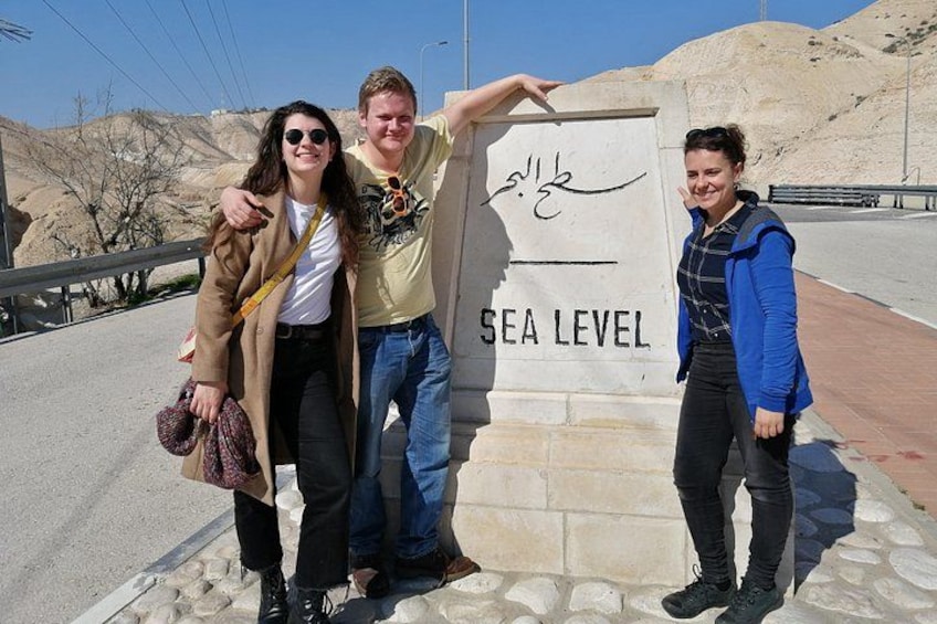 Three people standing in front of a sign that reads 'SEA LEVEL'. 5