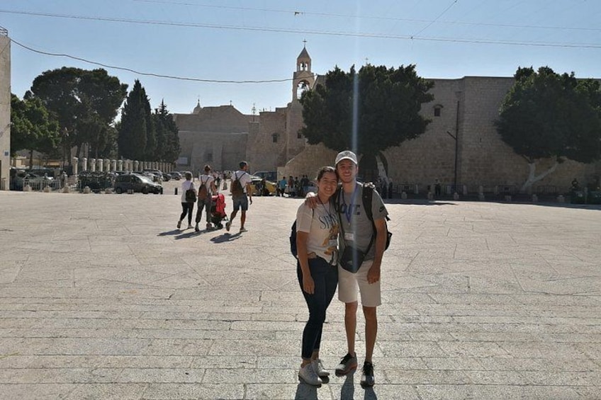 A group of people in a historical square with a prominent building in the background. 4