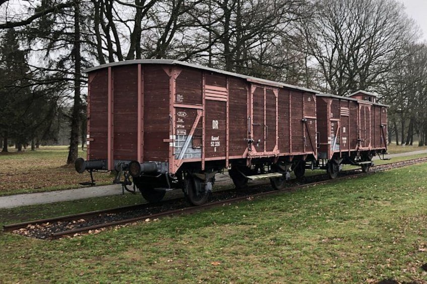 A red caboose train car on a track in a park. 1