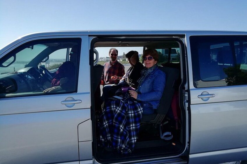 A white van with its door open, revealing three people inside. 4