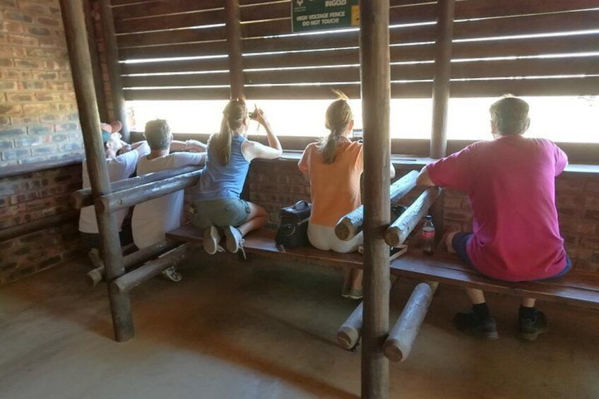 People sitting on wooden benches in a rustic setting with brick walls and wooden beams. 3