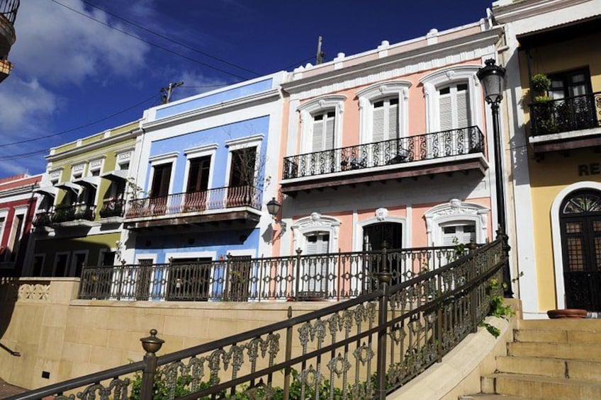 A row of colorful pastel houses with balconies, a wrought iron fence, and a street lamp. 3