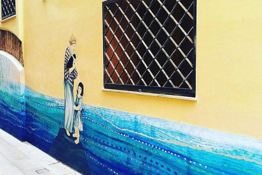 A mural of a woman and child on a yellow wall with a window. 3