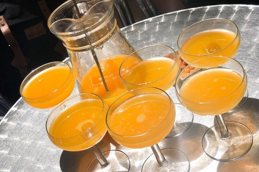 A glass pitcher and several glasses of orange juice on a metal tray. 5