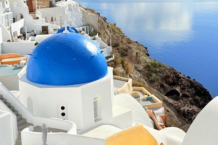 A coastal village with white buildings and a prominent blue dome. 5